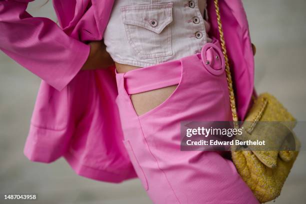 Gabriella Berdugo wears a gold large necklace, a beige ribbed shoulder-off top, a pale pink denim buttoned sleeveless corset gilet, a neon pink...