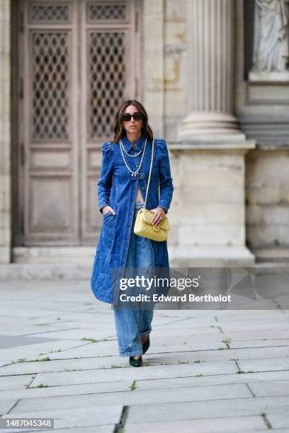 Gabriella Berdugo wears black squared sunglasses, a white pearls double long necklace from Whoboy, a beige ribbed shoulder-off cropped top, a navy...