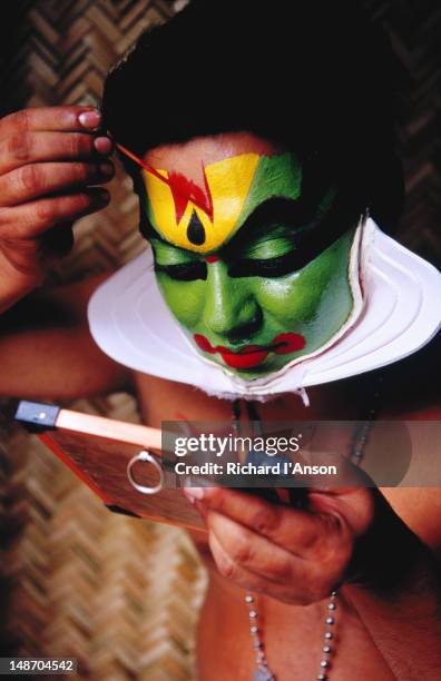 kathakali dancer applying make-up before performance. - traditional ceremony stock pictures, royalty-free photos & images