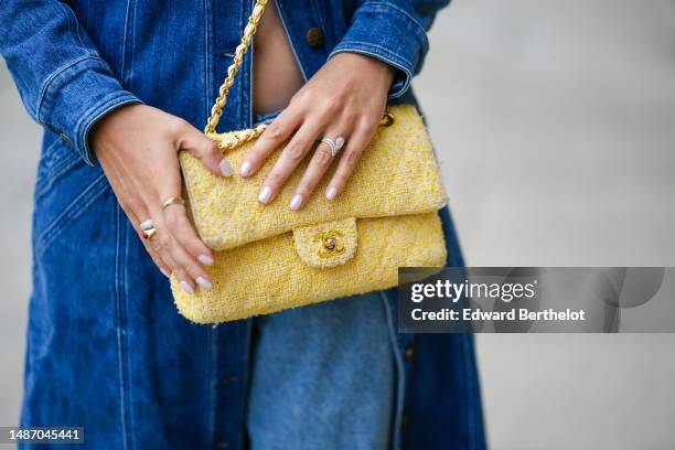 Gabriella Berdugo wears a navy blue denim belted buttons / puffy shoulder long jacket from Copenhagen Muse, a white and yellow tweed Timeless...