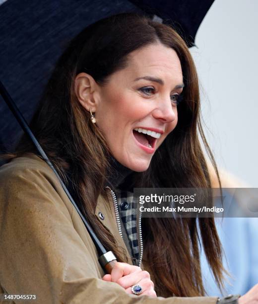 Catherine, Princes of Wales shelters under an umbrella whilst meeting members of the public as she visits Dowlais Rugby Club on April 27, 2023 in...
