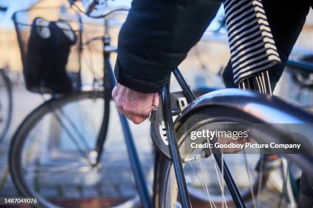 senior man locking up his bicycle in the city - bike lock stock pictures, royalty-free photos & images