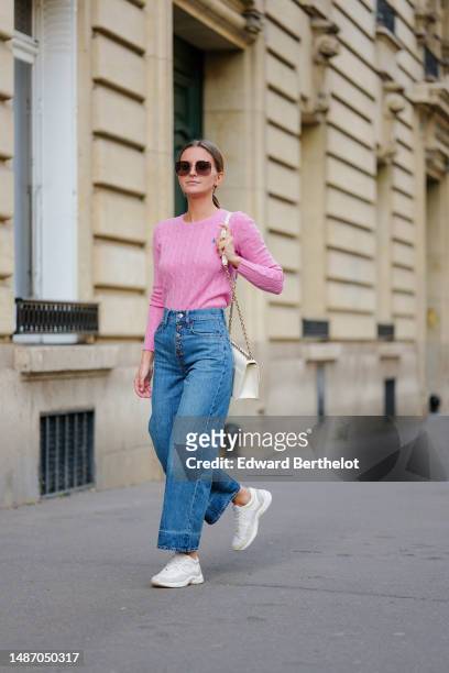 Diane Batoukina wears dark brown large squared sunglasses from Dior, a pale pink braided wool pullover from Ralph Lauren, blue faded denim / buttons...
