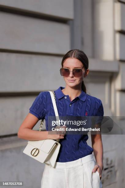 Diane Batoukina wears dark brown large squared sunglasses from Dior, a navy blue braided wool short sleeves polo shirt from Ralph Lauren, high waist...