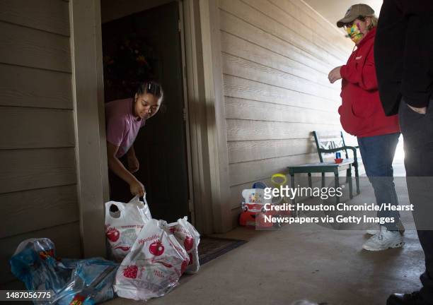 Briana Jones, left, picks up a bag of food delivered to her by Crowdsource Rescue's Terri Hackl Saturday, Feb. 20, 2021 in Spring. The volunteer...