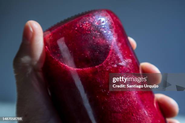 man holding a glass bottle with beet juice - biet stockfoto's en -beelden