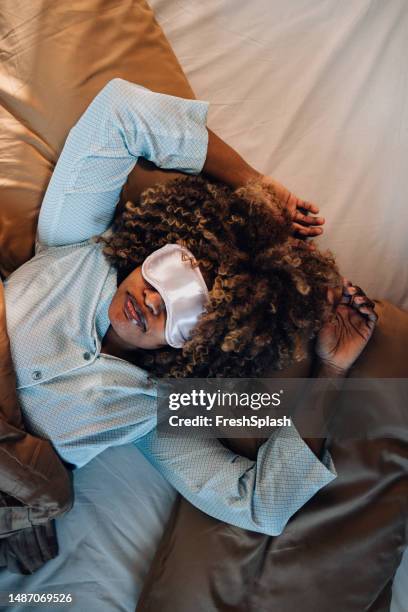 a from above view of a beautiful woman in pajamas lying on the cozy bed with a blindfold - nighttime routine stock pictures, royalty-free photos & images