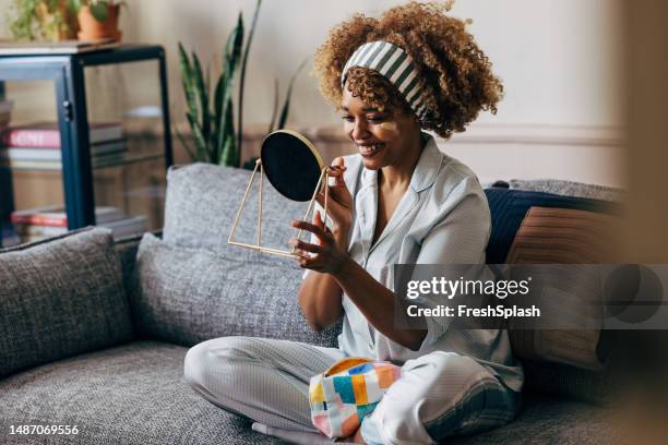 a happy beautiful woman in pajamas taking care of herself while relaxing at home - routine stock pictures, royalty-free photos & images