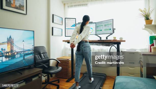 woman at home office is walking on under desk treadmill - treadmill test stockfoto's en -beelden