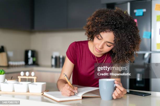 happy woman at home planning her day while drinking coffee - bullet journal stock pictures, royalty-free photos & images