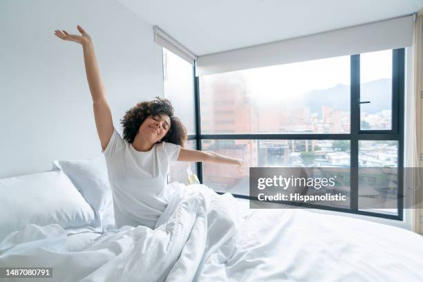 woman waking up in the morning and yawning in bed - matras stockfoto's en -beelden