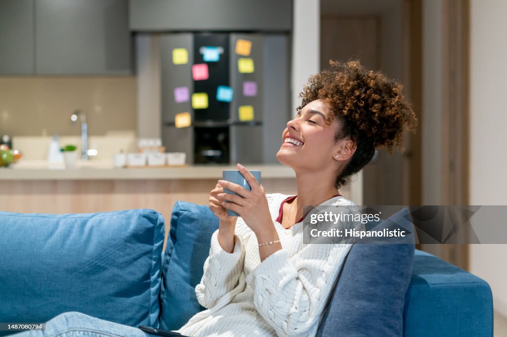 Happy woman relaxing at home and drinking a cup of coffee