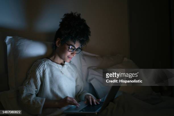 woman working late at a home in bed and using her laptop - authors night stockfoto's en -beelden