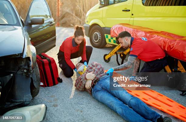 ambulance staff moving accident victim onto spinal board - cervical collar stock pictures, royalty-free photos & images