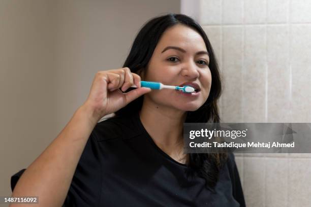 young woman brushing her teeth. - toothbrush stock pictures, royalty-free photos & images