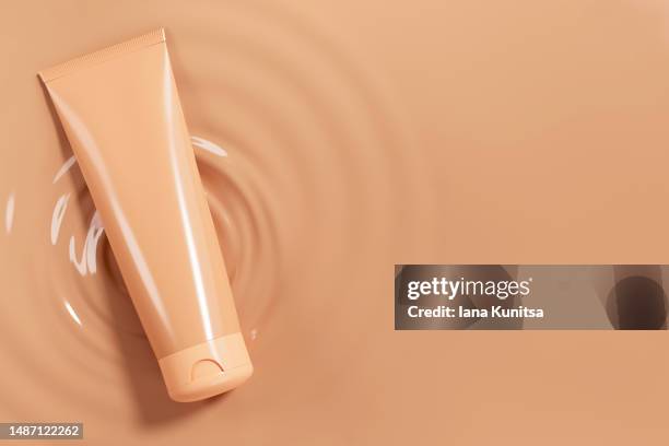 beige tube, bottle of foundation for skin, face cream on brown textured background. cosmetic products for makeup and skincare. 3d pattern. skin tone. copy space. place for text. - huidkleurig stockfoto's en -beelden