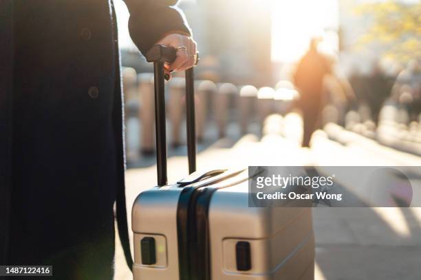 close-up of female hand carrying luggage in the city - suitcase close stock-fotos und bilder