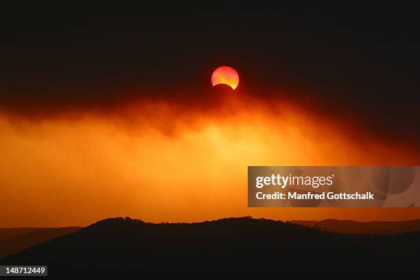 partial solar eclipse on 04/12/2002 through thick plume of bushfire smoke over broken bay. - éclipse solaire photos et images de collection