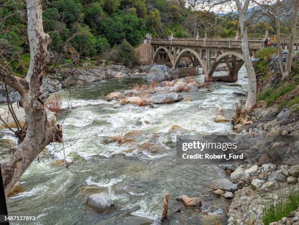 rapids on the kaweah river in three forks california by historic bridge built by the ccc showing heavy snow runoff from mineral king and sequoia national park in april 2023 - smeltende sneeuw stockfoto's en -beelden