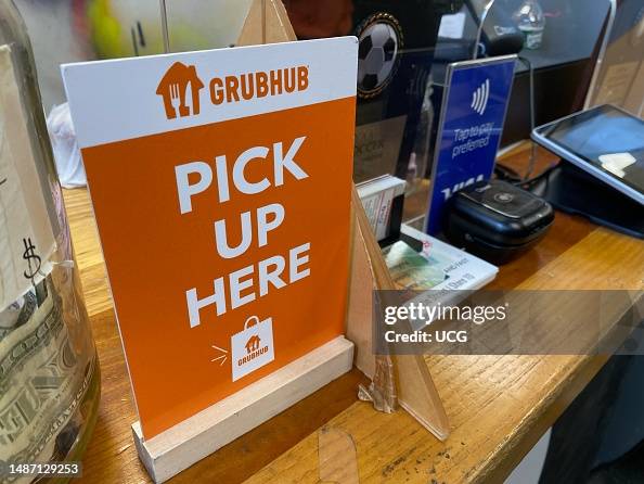 Grubhub pick up area sign, tap payment scanner and tips jar at The Nut Factory, Queens, New York Grubhub pick up area sign, tap payment scanner and tips jar at The Nut Factory, Queens, New York