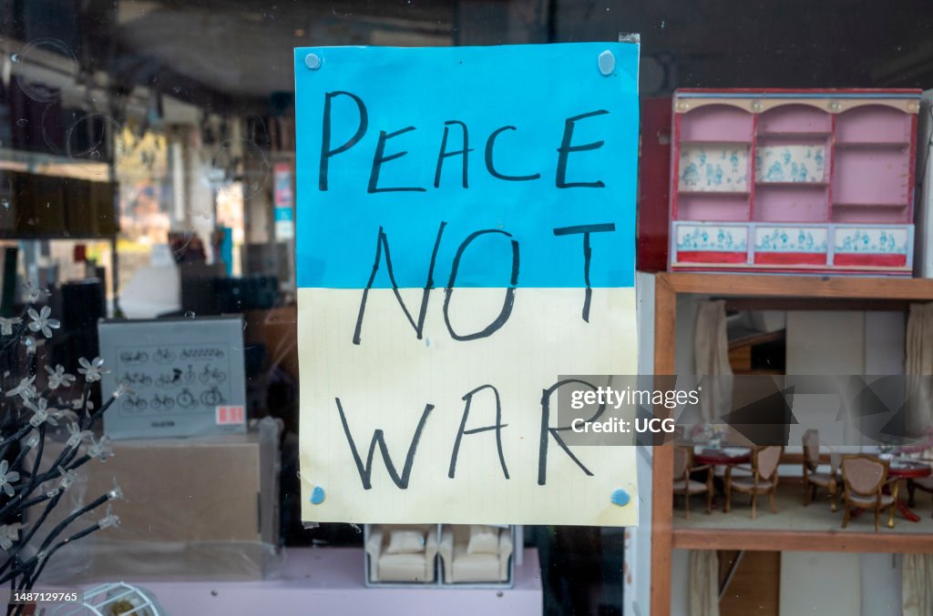 A sign in the colors of the Ukraine flag in a shop window in Steyning, West Sussex, UK, calling for Peace not War.