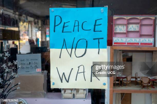 Sign in the colors of the Ukraine flag in a shop window in Steyning, West Sussex, UK, calling for Peace not War.