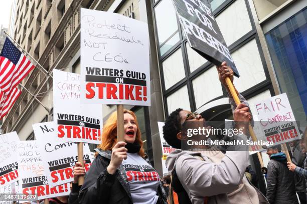 Members of the Writers Guild of America East hold signs as they walk on the picket-line outside of the Peacock NewFront on May 02, 2023 in New York...