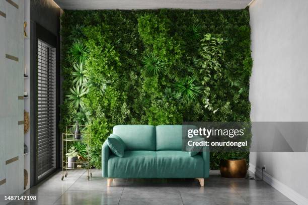 grünes wohnzimmer mit türkisfarbenem sofa, vertikalem garten und fliesenboden - vertical garden stock-fotos und bilder