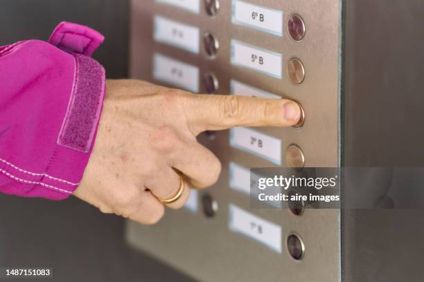 close-up of a woman's hand touching her finger to the doorbell button of a doorman in a house, side view - door close button stock-fotos und bilder