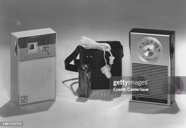 Couple of portable AM transistor radios, showing a case, a 9 volt battery and an earplug.
