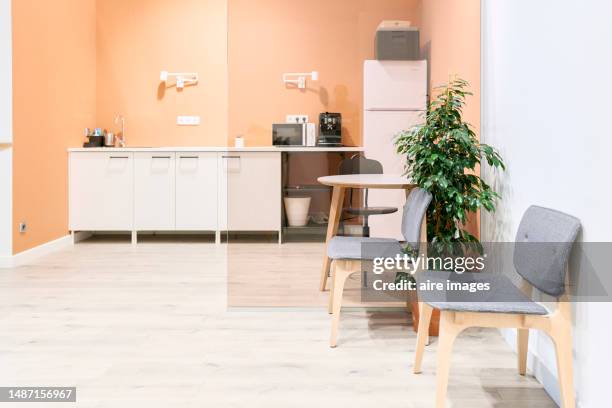 front view of a coffee space in an office with microwave, kettle and refrigerator, without people in the chairs. - refrigerator front stock pictures, royalty-free photos & images