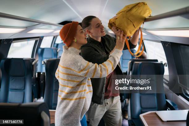 young woman couple placing their bag on the luggage space in train coach - tåginteriör bildbanksfoton och bilder