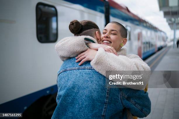 woman leaving and embracing her friend on train station - train arrival stock pictures, royalty-free photos & images