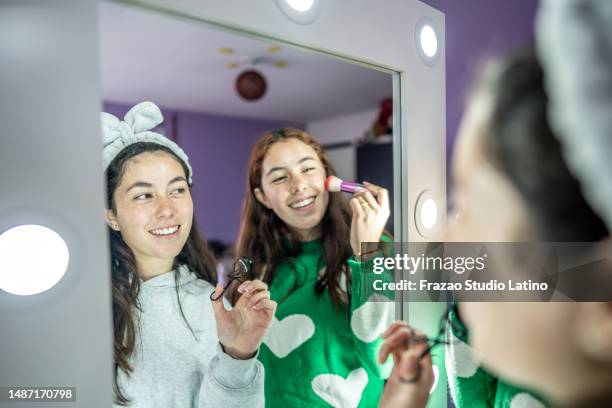 twin sisters looking to the mirror while pass make-up at bedroom - vanity mirror stock pictures, royalty-free photos & images