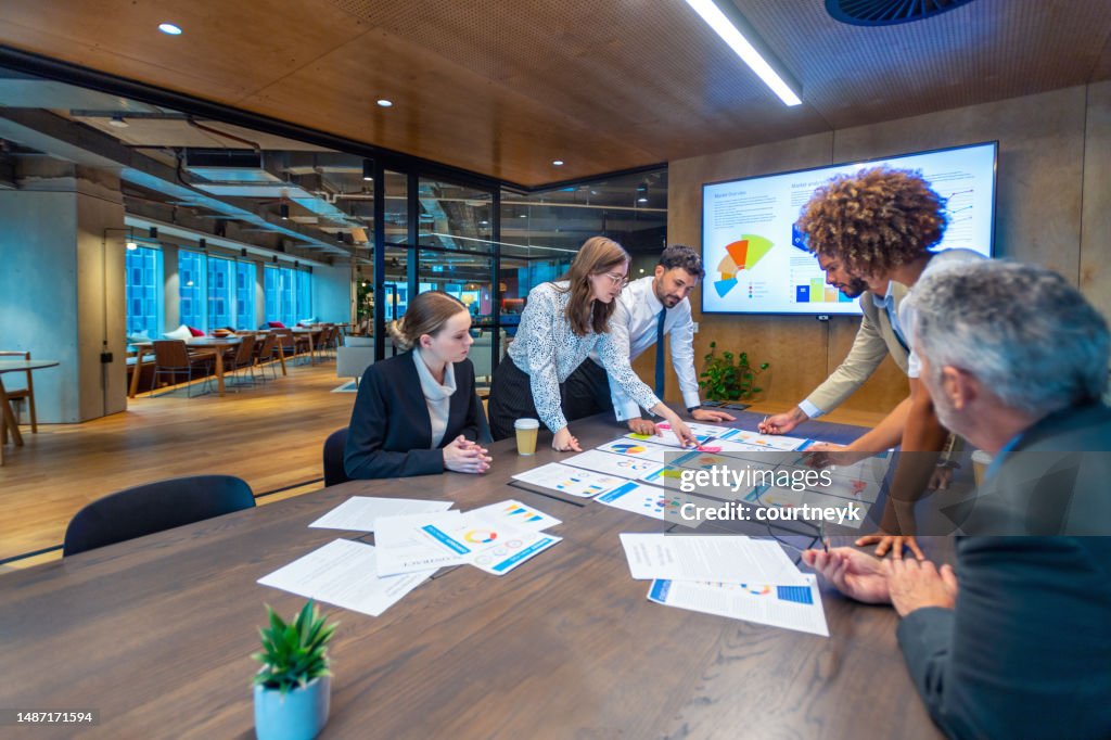 Paperwork and group of peoples hands on a board room table at a business presentation or seminar.