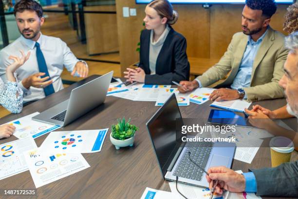 . the documents on the conference table have financial or marketing figures, graphs and charts on them. - round table imagens e fotografias de stock