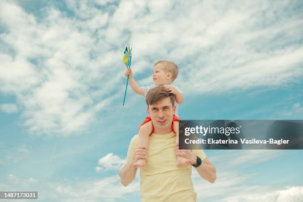 child with with paper windmill sitting  on dad's neck - eastern europe ストックフォトと画像