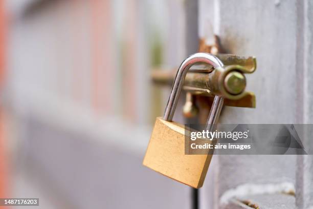 lock with golden padlock placed on a door somewhere, seen from a front angle with a blurred background - cadenas photos et images de collection
