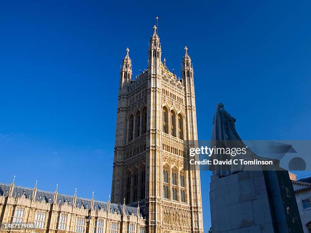 victoria tower, highest tower of the houses of parliament, towering above statue of king george v. - george v of great britain stock pictures, royalty-free photos & images