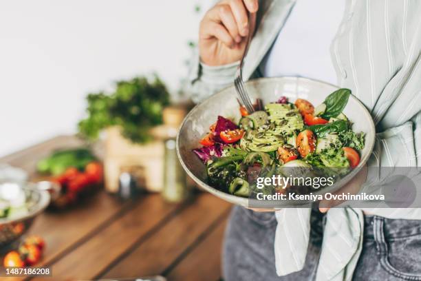 woman mixing delicious superfood salad ingredients with wooden spoons in kitchen - serving size 個照片及圖片檔