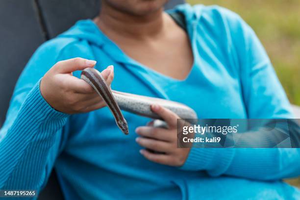 young asian woman holding pet snake, sitting outdoors - adirondack chair closeup stock pictures, royalty-free photos & images