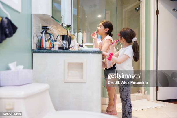 family love: two sisters brushing their teeth side by side - fluor stockfoto's en -beelden