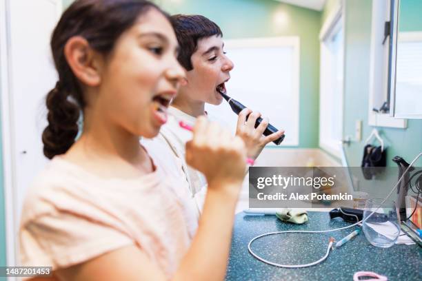 two kids using toothbrushes to clean their teeth in the bathroom - fluor stockfoto's en -beelden