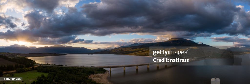 Aerial shot of a bridge over a large dam at sunset