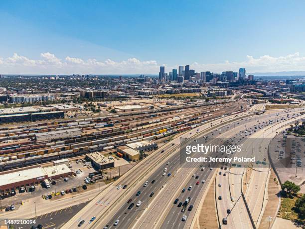 a high angle view of interstate 25 traffic passing a large railyard with trains and freght cars north of denver, colorado near "the mousetrap" highway interchange - commerce city colorado stock pictures, royalty-free photos & images