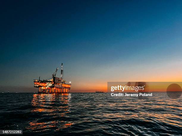 linksbündiges foto einer offshore-ölbohrinsel in der abenddämmerung in der nähe von huntington beach - drilling rig stock-fotos und bilder