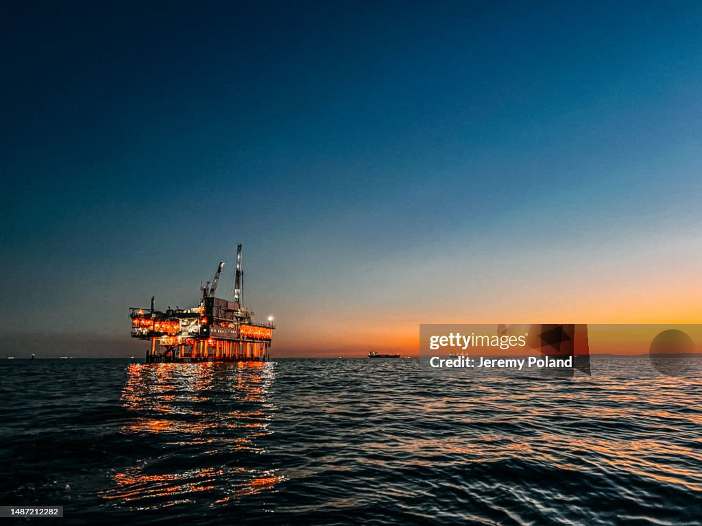 Photo spatiale de copie alignée à gauche d’une plate-forme de forage pétrolier offshore au crépuscule près de Huntington Beach