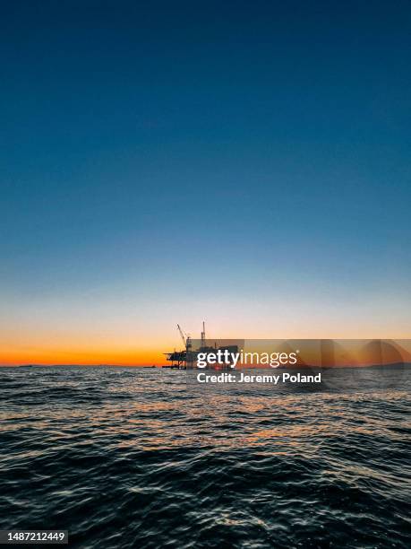 stunning ultra wide-angle photo on the ocean of offshore oil drilling rig in silhouette near huntington beach, california - opec stock pictures, royalty-free photos & images