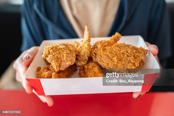 cropped shot of woman holding a paper box with pieces of fried chicken before eating. - gefrituurde kip stockfoto's en -beelden