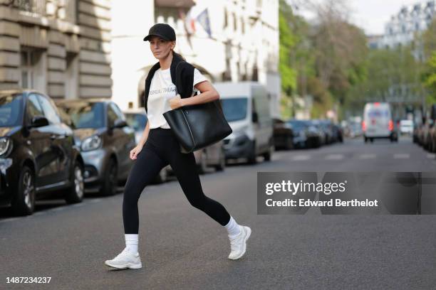 Diane Batoukina wears a black with embroidered NY logo pattern cap from New Era, a white with black faded logo print pattern t-shirt from Saint...